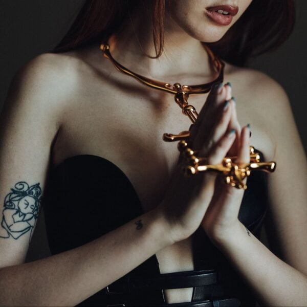 Collier et menottes BDSM en métal doré UPKO – Brigade Mondaine Paris Collier et menottes BDSM UPKO en métal doré portés ensemble dans une mise en scène éditoriale Brigade Mondaine Paris