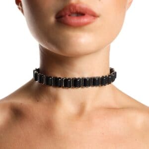 Black ANOESES choker worn around the neck of a female model, featuring aligned metal rings and an adjustable structure, high-end fetish aesthetic Brigade Mondaine Paris.