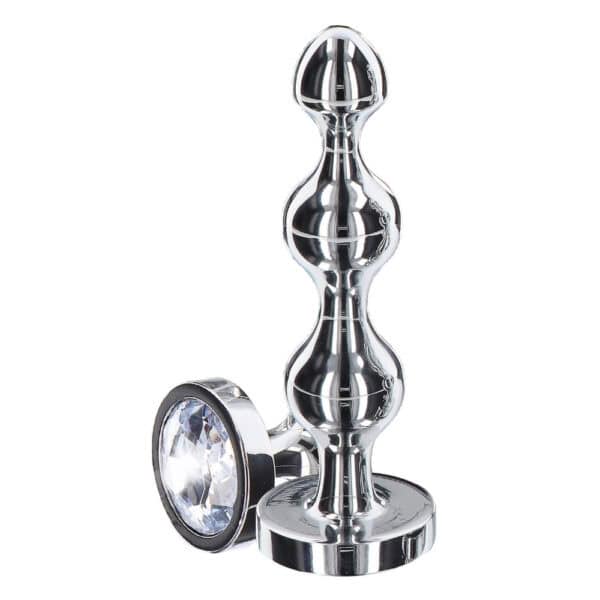Analplug in poliertem Metall mit transparentem, facettiertem Kristall, ausladender Basis und glänzendem Finish, präsentiert von Brigade Mondaine Paris.