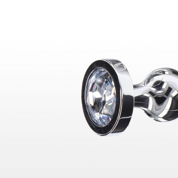 Analplug in poliertem Metall mit transparentem, facettiertem Kristall, ausladender Basis und glänzendem Finish, präsentiert von Brigade Mondaine Paris.