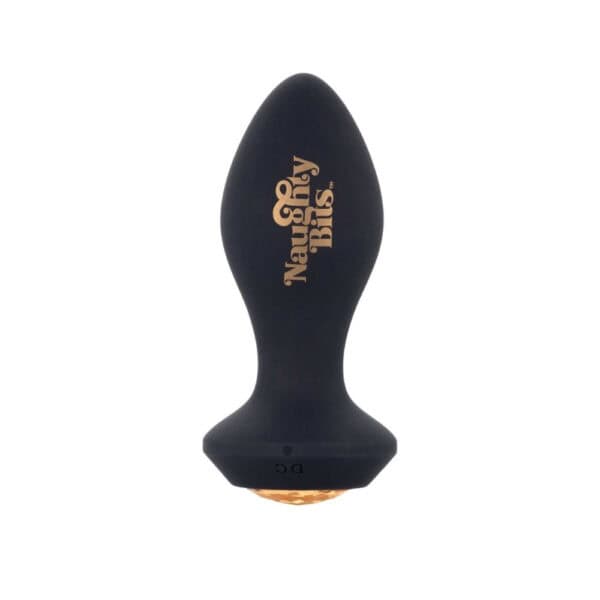 Schwarzer Analplug aus Silikon mit einer Basis, die mit einem facettierten bernsteinfarbenen Schmuckstück verziert ist, in der Hand gehalten, angeboten von Brigade Mondaine Paris.