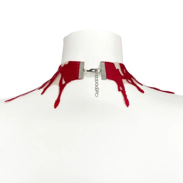Choker Blood VIDEO SCHWARZ Brigade Mondaine Paris rot Spitze Choker Blood rot VIDE NOIR präsentiert bei Brigade Mondaine Paris, nudefarbener Tüll bestickt mit fließenden roten Motiven, an einer Schaufensterpuppe getragen, mit einem zentralen roten facettierten Anhänger.