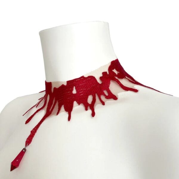 Choker Blood VIDEO SCHWARZ Brigade Mondaine Paris rot Spitze Choker Blood rot VIDE NOIR präsentiert bei Brigade Mondaine Paris, nudefarbener Tüll bestickt mit fließenden roten Motiven, an einer Schaufensterpuppe getragen, mit einem zentralen roten facettierten Anhänger.
