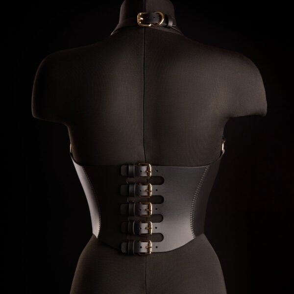 Corset Bondage HOSTIA IINFYNII – Brigade Mondaine Paris Corset Bondage HOSTIA IINFYNII noir avec sangles et anneaux métalliques porté sur un top en mesh, pièce structurée proposée par Brigade Mondaine Paris