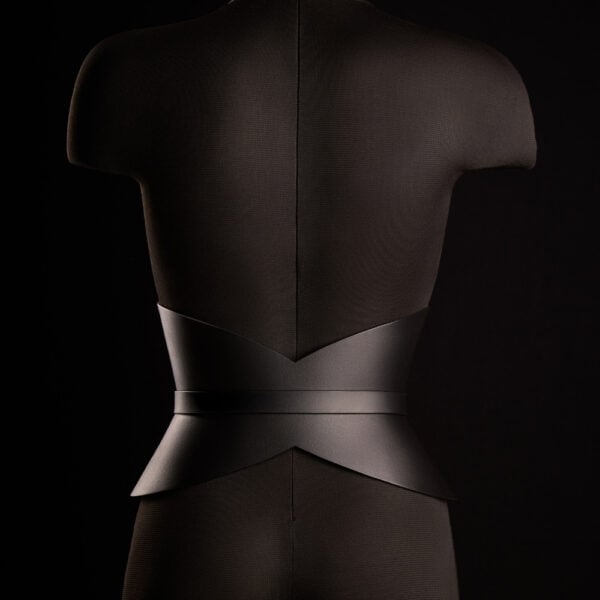 Corset ceinture HUDIA IINFYNII en cuir noir avec fermoir métallique infini porté sur un tailleur noir, accessoire structurant et graphique proposé par Brigade Mondaine Paris