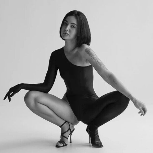 DEXTRA ANOESES catsuit worn by a model in squatting pose, asymmetrical black second skin, selection Brigade Mondaine Paris.