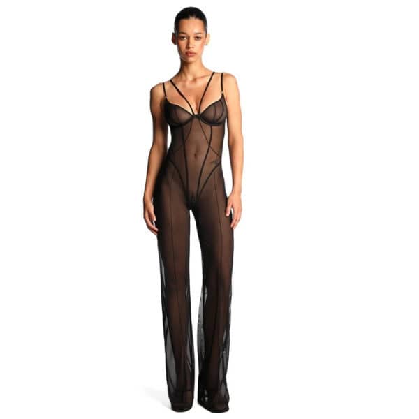Catsuit ANOESES en mesh noir porté par un modèle féminin debout, coupe près du corps avec bretelles fines, lignes graphiques verticales et jambes longues transparentes, esthétique fétiche haut de gamme Brigade Mondaine Paris.