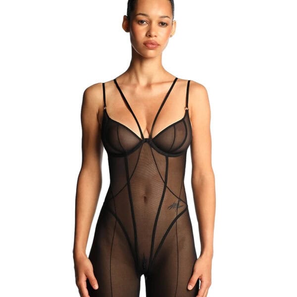 Catsuit ANOESES en mesh noir porté par un modèle féminin debout, coupe près du corps avec bretelles fines, lignes graphiques verticales et jambes longues transparentes, esthétique fétiche haut de gamme Brigade Mondaine Paris.