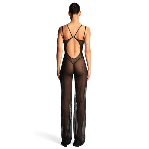 Catsuit ANOESES en mesh noir porté par un modèle féminin debout, coupe près du corps avec bretelles fines, lignes graphiques verticales et jambes longues transparentes, esthétique fétiche haut de gamme Brigade Mondaine Paris.