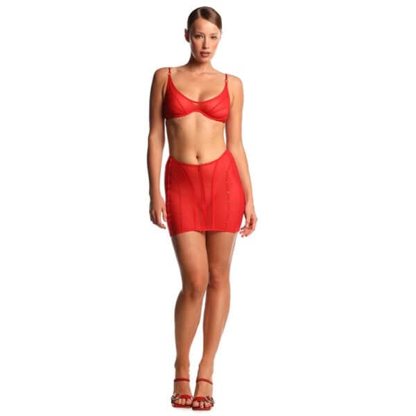 Conjunto ANOESES compuesto por sujetador y falda de tul rojo, llevado por una modelo de pie, corte entallado, líneas estructuradas y detalles gráficos, estética fetichista de alta gama Brigade Mondaine Paris.
