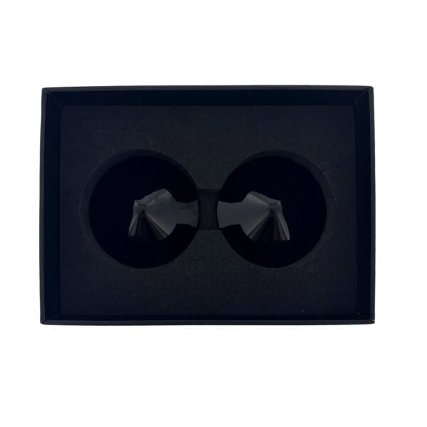 Modèle portant des cache-tétons noirs Seduction à surface lisse avec pointe conique centrale, photographiée sur fond blanc dans une mise en scène épurée et contemporaine.