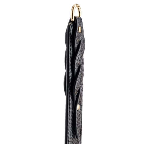 Model trägt einen transparenten schwarzen Body und hält ein BDSM-Paddle aus schwarzem Leder mit strukturiertem Finish. Fotografiert vor einem weißen Hintergrund in einer schlichten und eleganten Inszenierung.