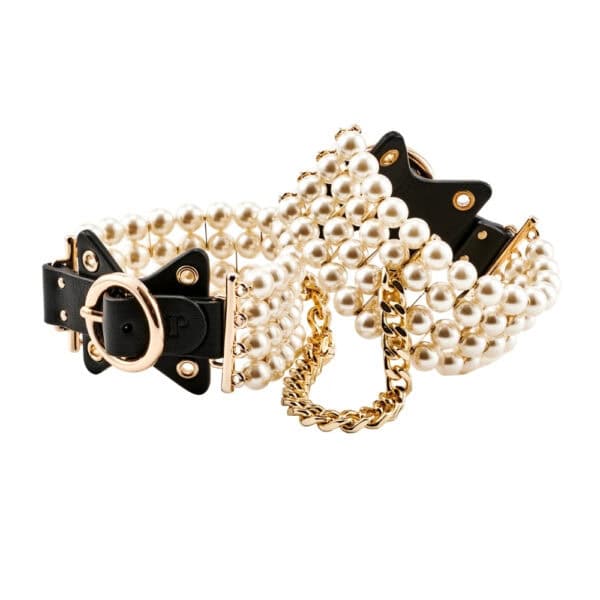 Tobilleras de cuero negro adornadas con perlas y unidas por una cadena dorada, llevadas por la modelo, ofrecidas por Brigade Mondaine Paris.