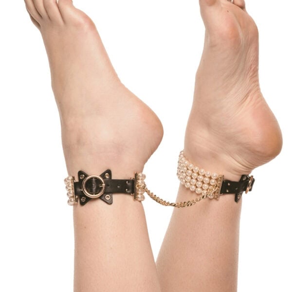 Tobilleras de cuero negro adornadas con perlas y unidas por una cadena dorada, llevadas por la modelo, ofrecidas por Brigade Mondaine Paris.
