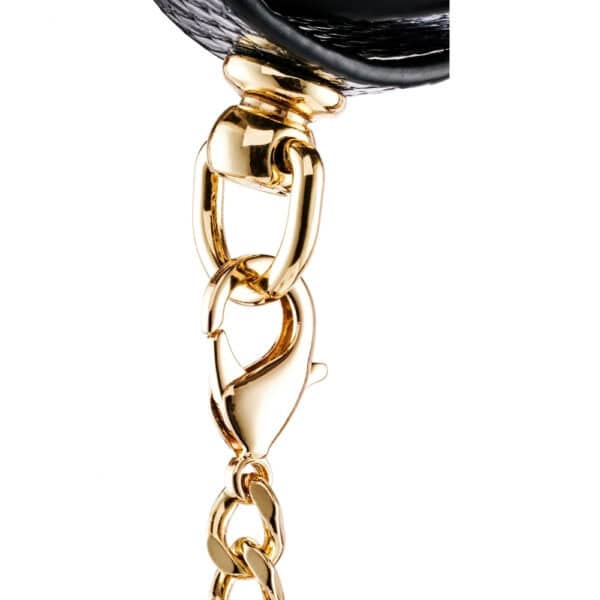 Modèle portant des menottes BDSM noires pour poignets avec chaîne dorée, accessoire de contrainte proposé par Brigade Mondaine Paris.