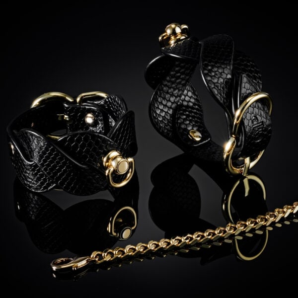 Modèle portant un collier BDSM noir texturé avec chaîne dorée et dragonne assortie, accessoire de contrainte proposé par Brigade Mondaine Paris.