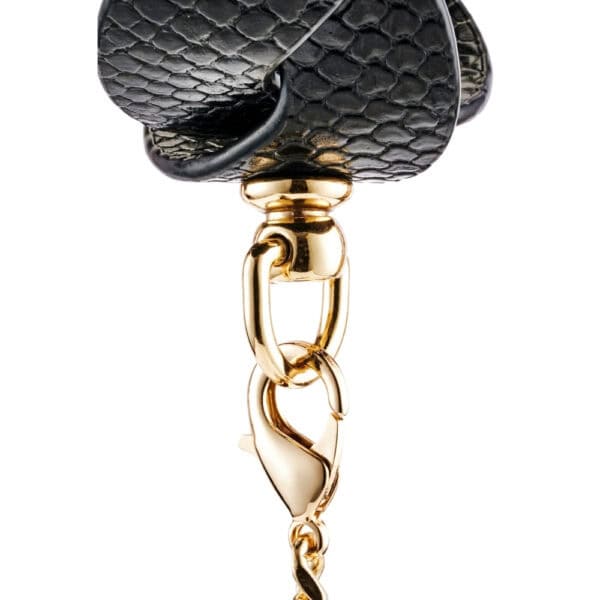 Model wearing a textured black BDSM necklace with gold chain and matching lanyard, restraint accessory offered by Brigade Mondaine Paris.