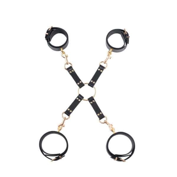BDSM-Hogtie aus schwarzem Leder und hochwertigen Goldbeschlägen BDSM-Hogtie aus schwarzem Leder, bestehend aus vier Riemen, die durch einen goldenen Mittelring verbunden sind. Er ist mit Metallkarabinern zur Befestigung ausgestattet.