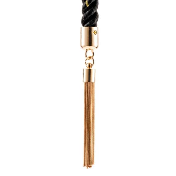 BDSM Seil schwarz Luxus goldene Details | Brigade Mondaine Schwarzes, gedrehtes BDSM-Seil mit goldenen Einlagen, das mit einem Lederriemen und einer Metallschnalle geschlossen wird, mit goldenen Verzierungen und Pompons versehen ist und auf schwarzem Hintergrund präsentiert wird.