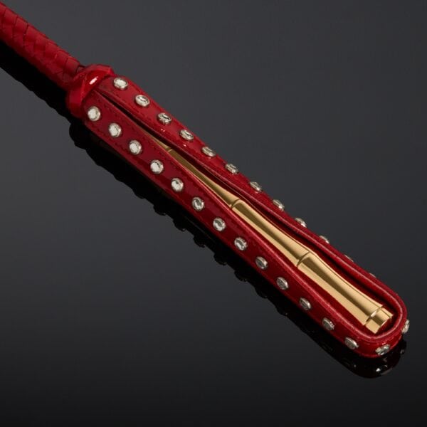 Cravache en vernis rouge HOUSE OF SXN avec manche rigide et extrémité plate, accessoire BDSM haut de gamme proposé par Brigade Mondaine Paris.