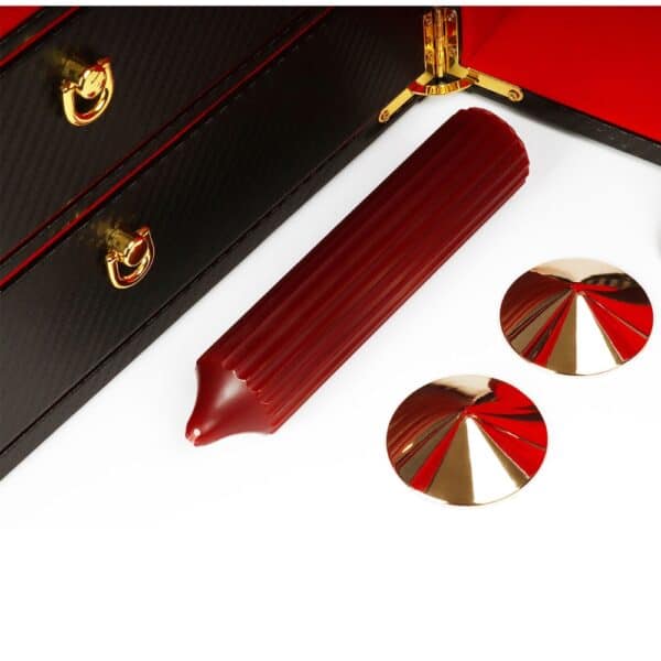 Caja BDSM abierta de cuero negro con interior rojo, que incluye un conjunto de accesorios variados como esposas, correas, fustas y cadenas, ordenados en una estética de lujo.