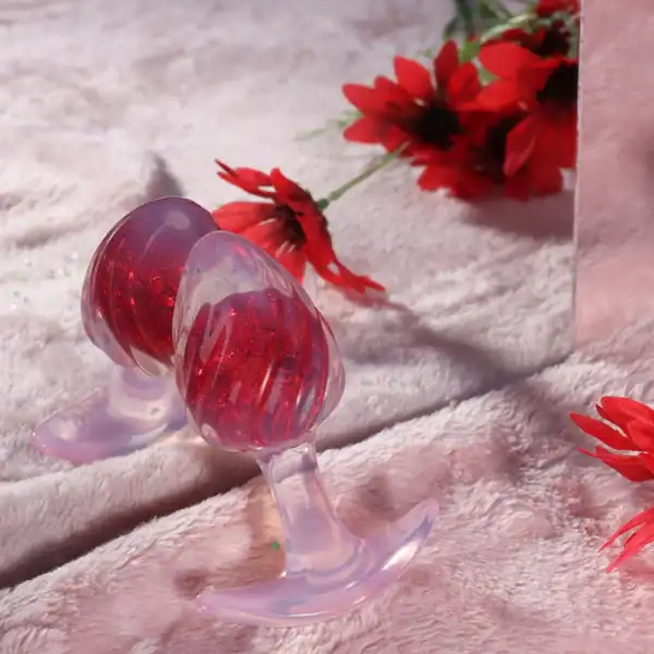 Plug en silicone rouge LIEBE SEELE avec surface spiralée et base transparente évasée, tenu en main sur fond blanc, vue produit détaillée