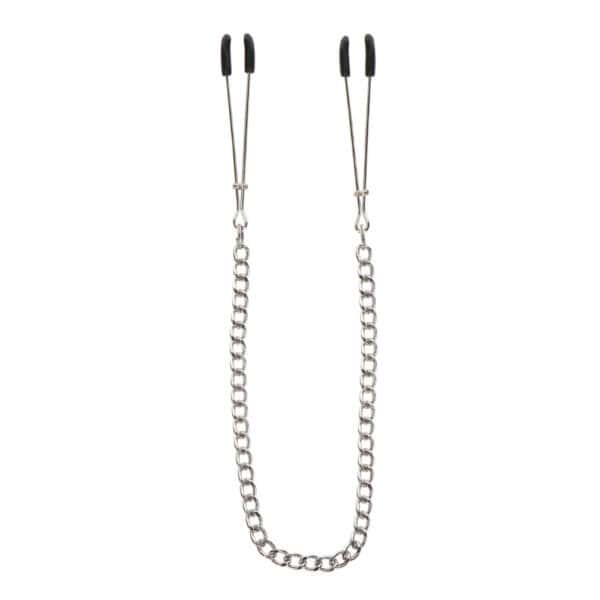 Modell trägt Nippelklemmen aus Metall, die mit einer dünnen Kette verbunden sind. Fotografiert vor einem einfarbigen Hintergrund mit einem auf die Büste zentrierten Bildausschnitt.