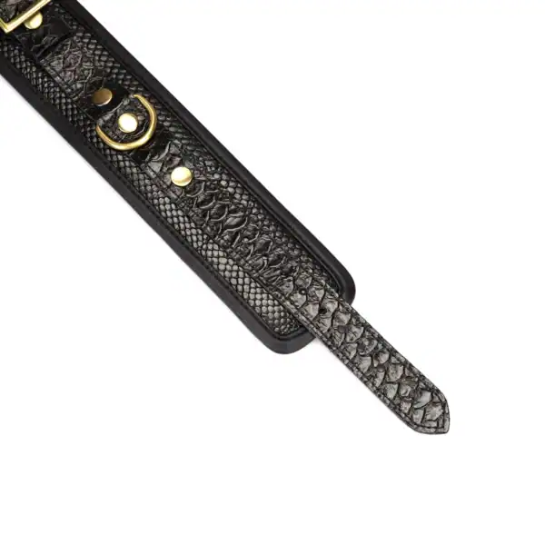 Handschellen aus schwarzem, krokogeprägtem Leder LIEBE SEELE mit Innenfutter und goldener Kette, auf weißem Hintergrund