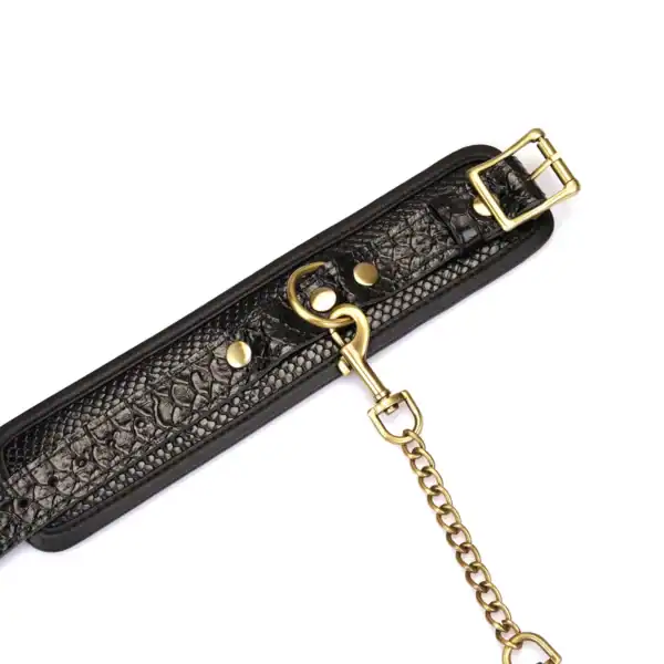 Handschellen aus schwarzem, krokogeprägtem Leder LIEBE SEELE mit Innenfutter und goldener Kette, auf weißem Hintergrund