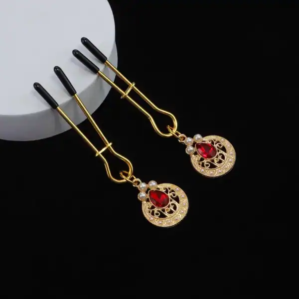 Nippelklemmen Perlenketten der Marke Liebe Seele, bestehend aus goldenen Klemmen, die mit einer Kette aus weißen Perlen mit eingefassten Ornamenten verbunden sind, präsentiert auf hellem Hintergrund in der Welt Brigade Mondaine Paris.