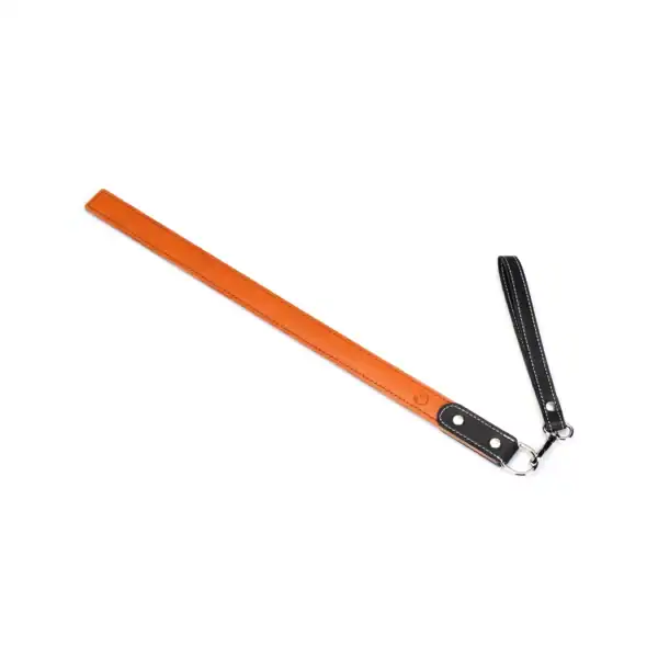LIEBE SEELE regla de azotar de cuero naranja con asa y correa, costuras en contraste, presentada sobre fondo blanco