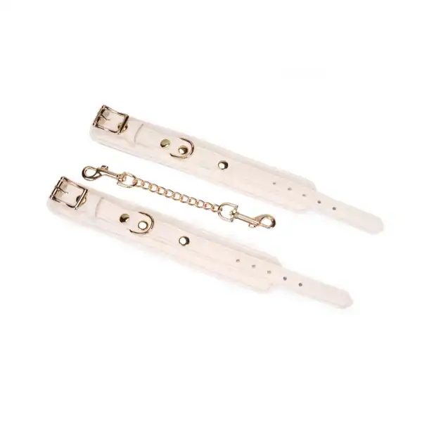 Boudoir Amor handcuffs by Liebe Seele, in light-colored leather with gold chain and snap hooks, presented flat on a light-colored background in the Brigade Mondaine Paris universe.