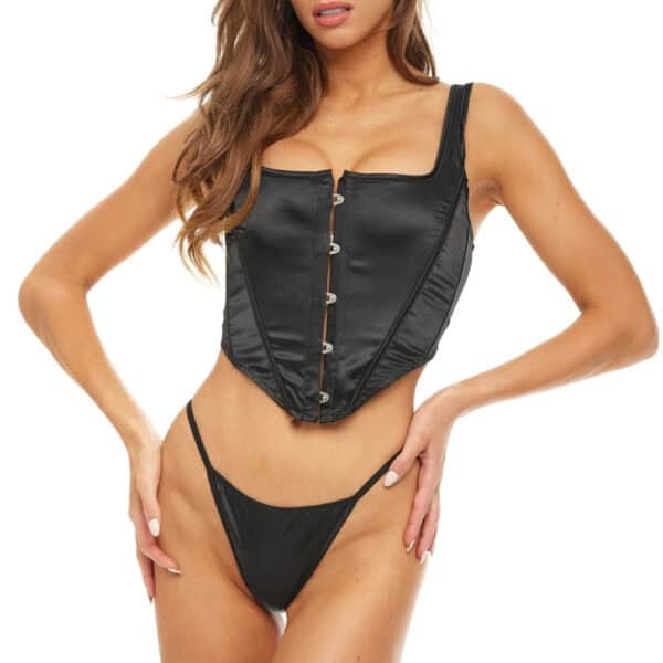 Model wearing a fitted black corset with front clips and wide straps, paired with minimalist bottoms, on a light background.