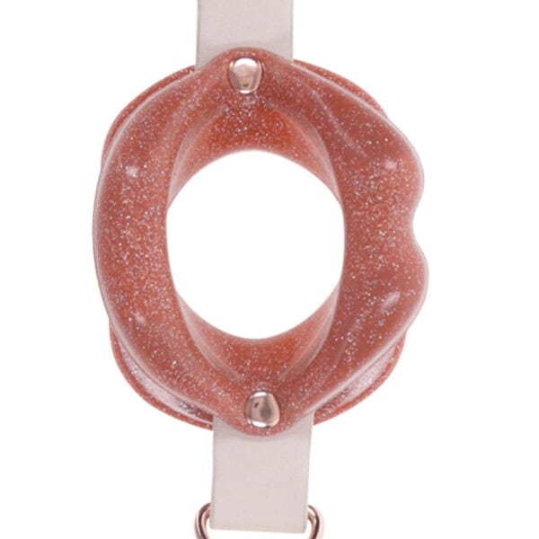 Open gag in lip design with clear strap and metal finishes, presented by Brigade Mondaine Paris on clear background.