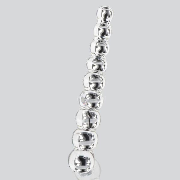 Dildo aus durchsichtigem Glas, bestehend aus aneinandergereihten Kugelformen, vertikal präsentiert auf weißem Hintergrund, mit einer glatten, glänzenden Oberfläche.