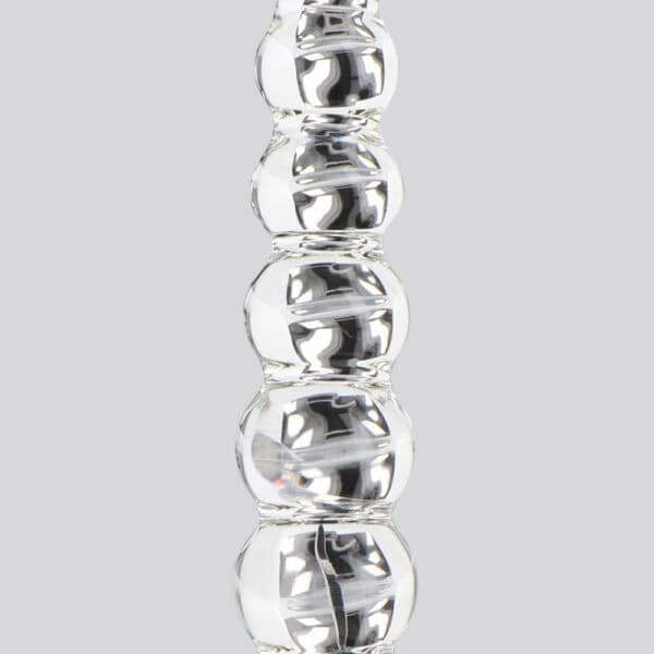 Dildo aus durchsichtigem Glas, bestehend aus aneinandergereihten Kugelformen, vertikal präsentiert auf weißem Hintergrund, mit einer glatten, glänzenden Oberfläche.
