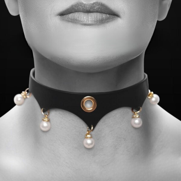 Close-up of a black leather BDSM necklace worn around the neck, adorned with gold rings and white beads, against a dark background, in an elegant, minimalist aesthetic.
