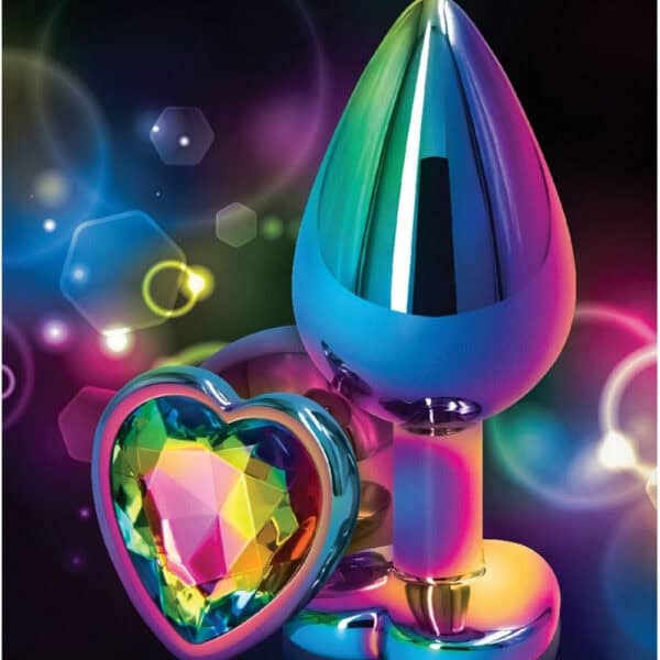 Analplug in mehrfarbigem Kristall mit dekorativer Basis in Form eines facettierten Herzens, präsentiert auf dunklem Hintergrund mit Lichteffekten und irisierenden Reflexen.