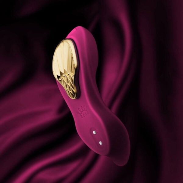 Plum-colored portable vibrator with gold details, ergonomic design and integrated controls, presented on a white background, selection Brigade Mondaine Paris.