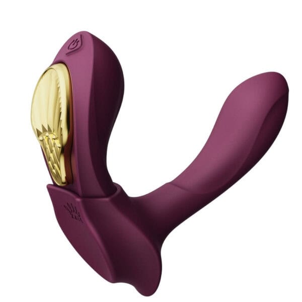 Plum-colored portable vibrator with gold details, ergonomic design and integrated controls, presented on a white background, selection Brigade Mondaine Paris.