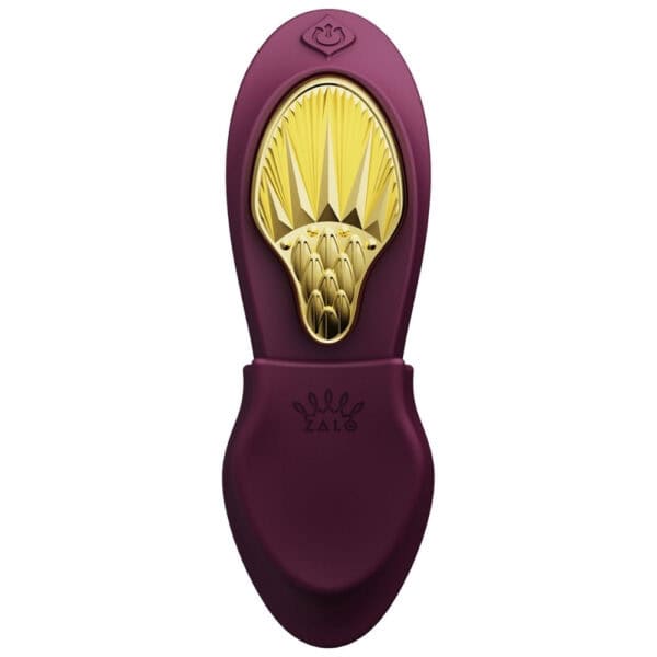 Plum-colored portable vibrator with gold details, ergonomic design and integrated controls, presented on a white background, selection Brigade Mondaine Paris.