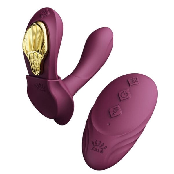 Plum-colored portable vibrator with gold details, ergonomic design and integrated controls, presented on a white background, selection Brigade Mondaine Paris.