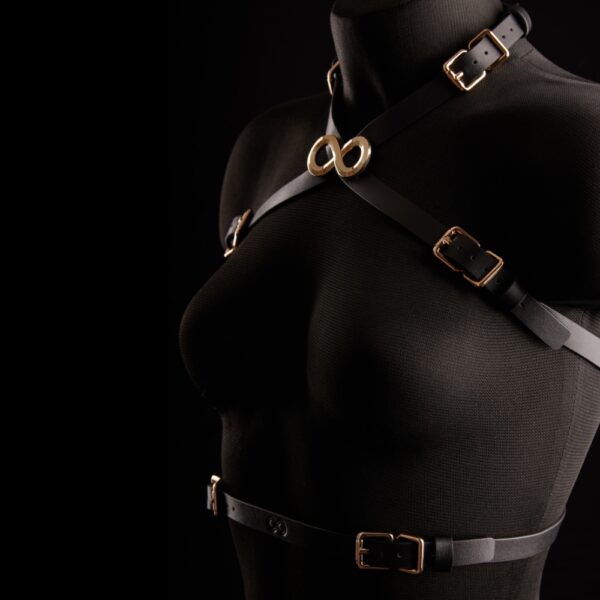 Arnés de 2 piezas IINFYNII Siyah presentado por Brigade Mondaine Paris, compuesto por un arnés de pecho y un arnés de cintura en cuero negro, correas ajustables y hebillas de metal dorado.
