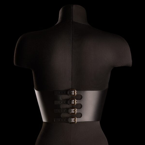 Bustier Neria negro de piel IINFYNII presentado en Brigade Mondaine Paris, colocado sobre un maniquí, entallado bajo el busto, tirantes finos ajustables y joya central dorada.