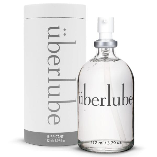 Lubrifiant Luxe Überlube Flacon en verre de lubrifiant luxe transparent avec spray, présenté avec son étui cylindrique blanc, sélection Brigade Mondaine Paris.