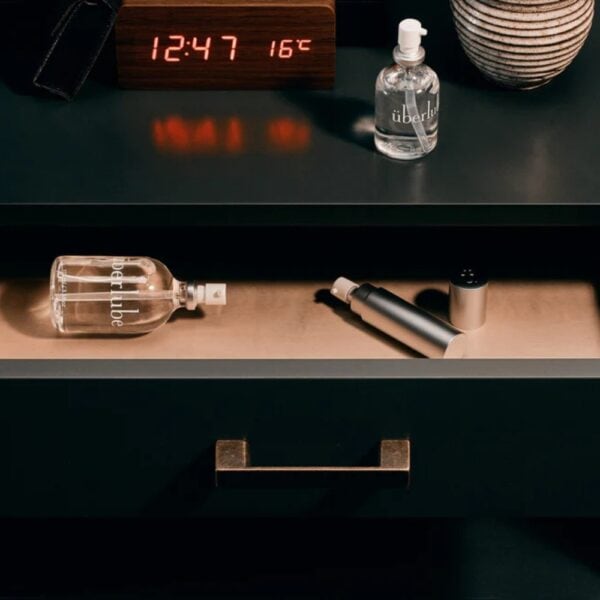 Lubrifiant Luxe Überlube Flacon en verre de lubrifiant luxe transparent avec spray, présenté avec son étui cylindrique blanc, sélection Brigade Mondaine Paris.