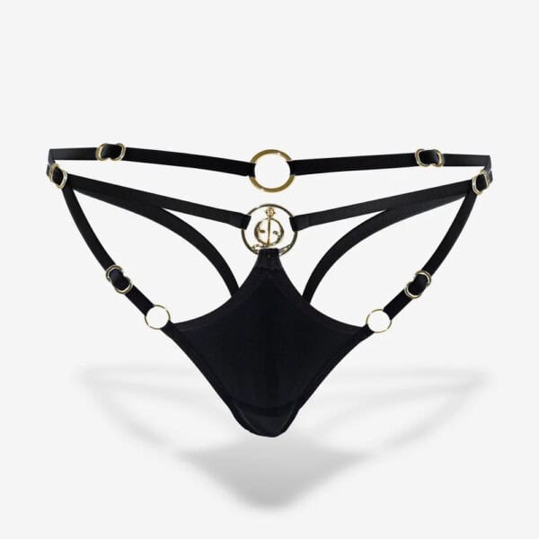 Tanga con anillos de oro QRUCIFIX - Brigade Mondaine Tanga QRUCIFIX negro con tiras finas, anillas metálicas doradas y diseño abierto, presentado sobre fondo blanco por Brigade Mondaine Paris.