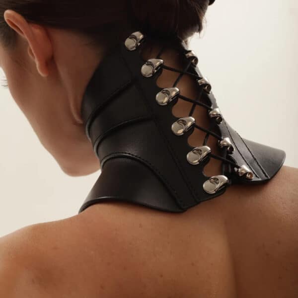 Halsband Posture Tenue RE:STRICT Brigade Mondaine Paris Rückendetail des Halsbands Posture Outfit aus schwarzem Leder RE:STRICT bei Brigade Mondaine Paris, halsbedeckender Schnitt, verstellbare Schnürung und Metallbeschläge, im Studio fotografiert.