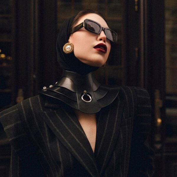 Halsband Posture Hold RE:STRICT Brigade Mondaine Paris Model trägt die RE:STRICT Posture Hold Halskette aus schwarzem Leder bei Brigade Mondaine Paris, ein steifes Stück, das den Hals bedeckt, zentraler Metallring, getragen mit einem schwarzen Mesh-Top im Studio.