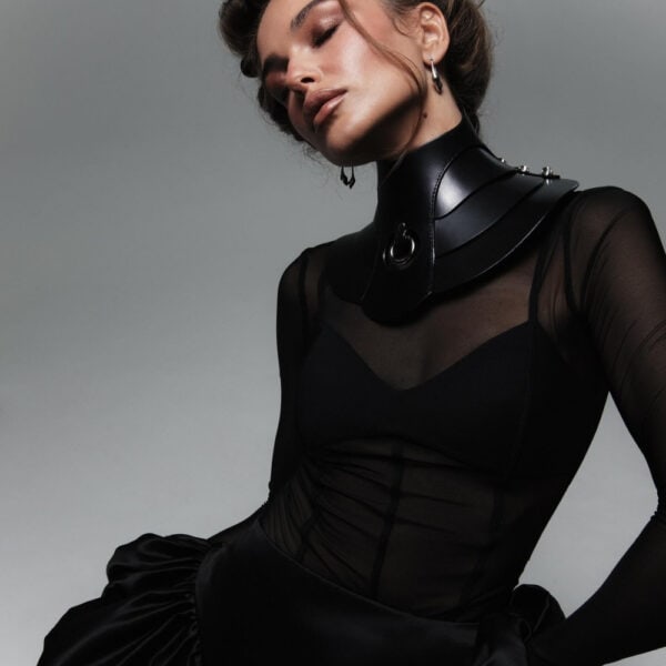 Halsband Posture Hold RE:STRICT Brigade Mondaine Paris Model trägt die RE:STRICT Posture Hold Halskette aus schwarzem Leder bei Brigade Mondaine Paris, ein steifes Stück, das den Hals bedeckt, zentraler Metallring, getragen mit einem schwarzen Mesh-Top im Studio.